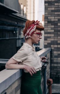 Side view of fashion model standing by retaining wall