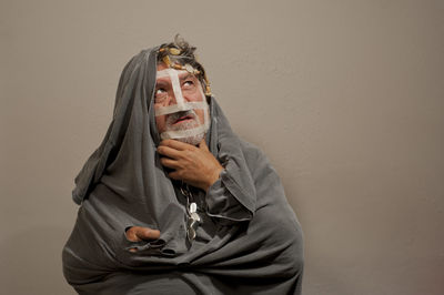 Portrait of man holding mask against wall