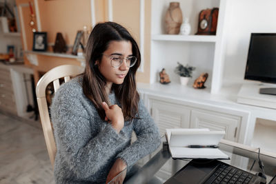 Young woman using phone while sitting on table