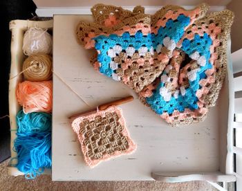 Directly above view of crochet needle amidst wools on table