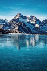 Scenic view of lake and snowcapped mountains against blue sky