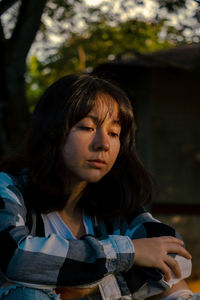 Mid adult woman looking away while sitting on tree