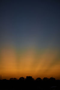Silhouette trees against dramatic sky during sunset