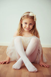 Portrait of smiling girl sitting on hardwood floor