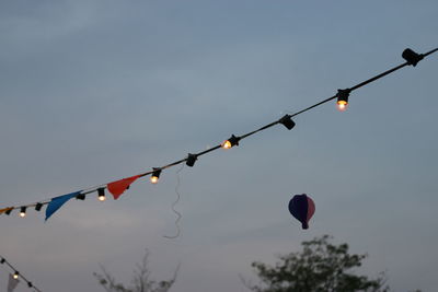 Low angle view of lighting equipment hanging against sky