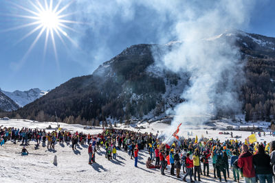 Crowd on snowcapped mountain during sunny day