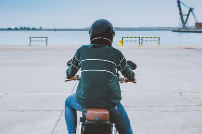 Rear view of man riding bicycle on sea