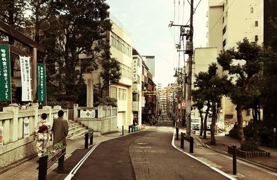 Road amidst trees in city against sky