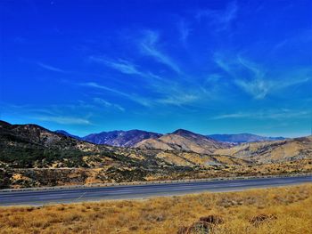 Scenic view of landscape and mountains against blue sky