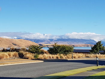 Road by trees against blue sky