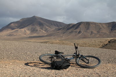 Bicycle parked on desert against sky