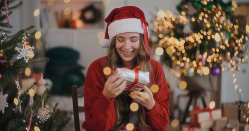 Portrait of smiling young woman holding christmas tree