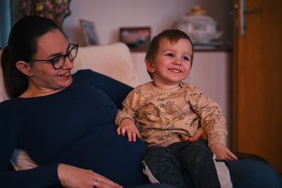 Pregnant mother holding her little toddler in a lap