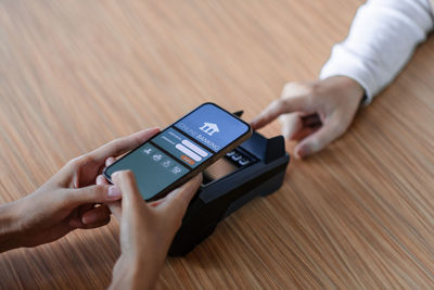 Midsection of woman using mobile phone on table