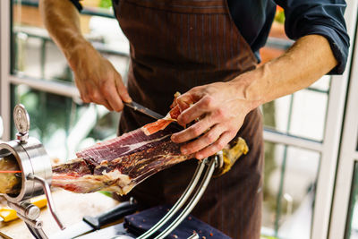 Midsection of man cutting meat