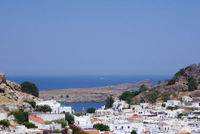 Townscape by sea against clear blue sky