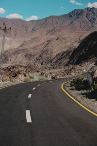 Road leading towards mountains against sky