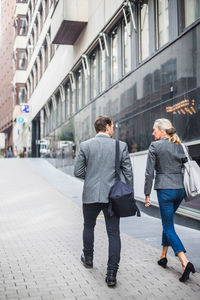 Rear view of business people walking by building