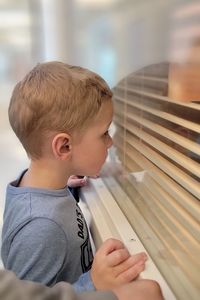 Side view of handsome boy looking in window for first view of newborn sibling