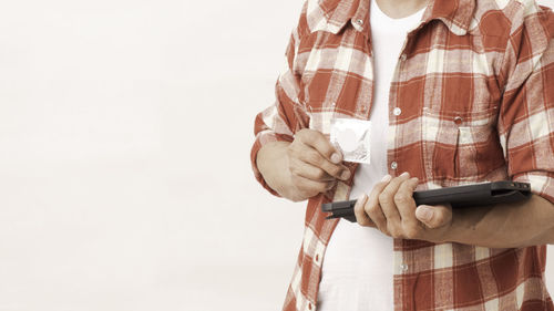 Midsection of man holding smart phone against white background