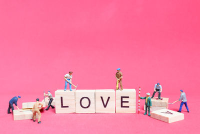 Figurines on toy blocks with love text against colored background