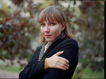 Portrait of beautiful woman standing against trees