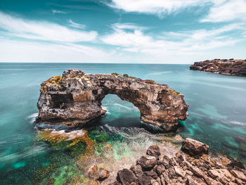 Rock formation in sea against sky