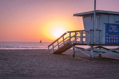 Lifeguard hut on beach against clear sky during sunset