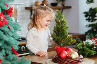 Portrait of girl playing with christmas tree at home