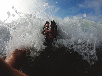 Waves splashing on shirtless man in sea
