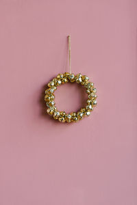Stylish christmas wreath of golden bells on a pink background with copyi space