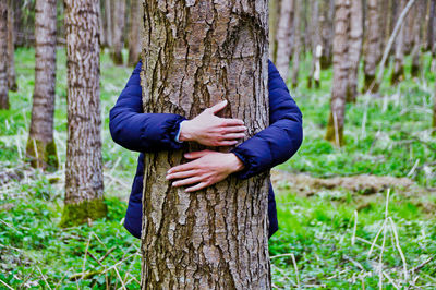 Woman hand by tree trunk in forest