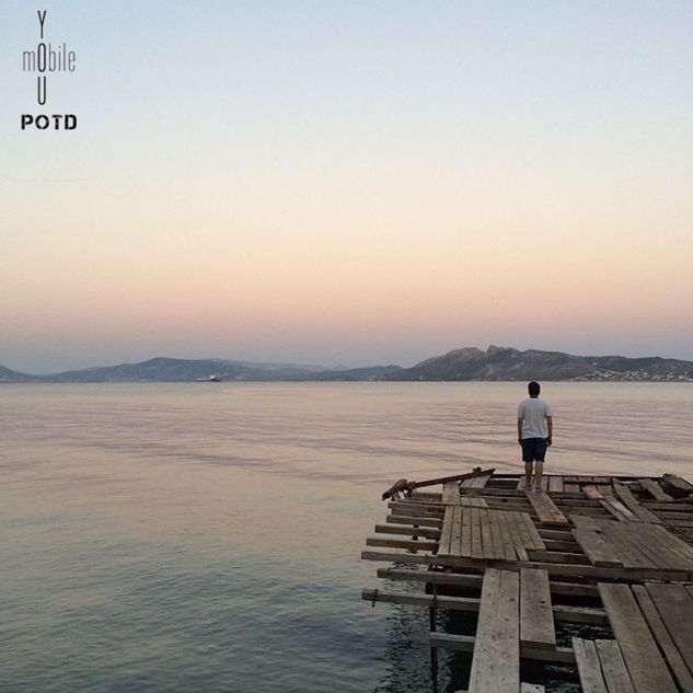 water, sea, clear sky, rear view, pier, copy space, lifestyles, tranquil scene, tranquility, standing, men, leisure activity, sky, scenics, full length, nature, sitting, lake