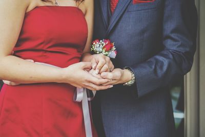 Midsection of couple holding hands at home