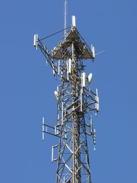 Low angle view of communications tower against clear blue sky