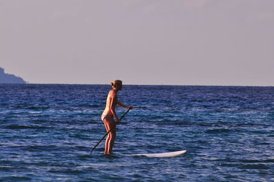 Full length of senior woman in sea against clear sky