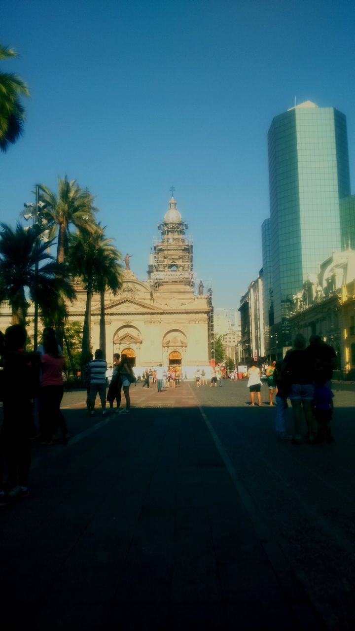 architecture, building exterior, built structure, city, clear sky, incidental people, tree, blue, travel destinations, famous place, statue, city life, sky, men, travel, sunlight, tourism, person, sculpture