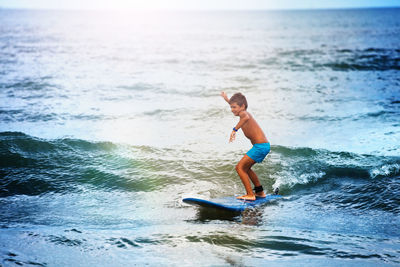 Side view of shirtless man surfing in sea