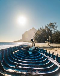 Woman sitting on shipwreck at beach