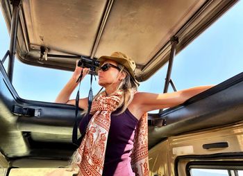 Mature woman looking through binoculars in safari vehicle