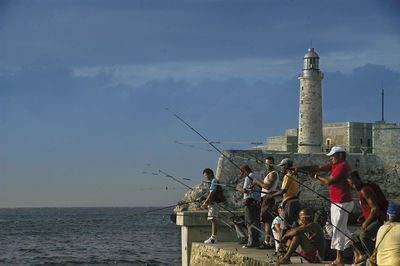 Men fishing in sea against sky