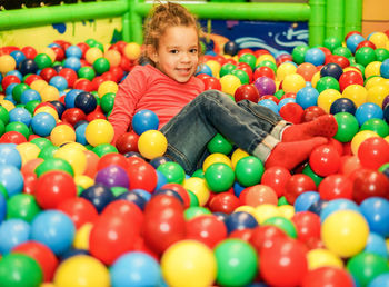 Portrait of girl playing with multi colored balls in pool