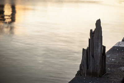 Wooden post on beach against sky during sunset