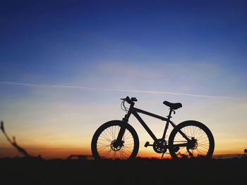 Silhouette bicycle against blue sky during sunset