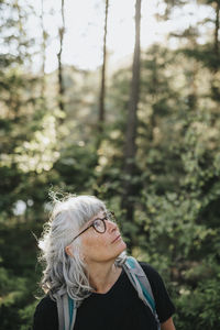 Senior woman looking around in forest