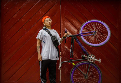 Young man with bicycle standing on umbrella