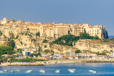 Sailboats in sea against buildings in city