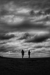 Silhouette people standing on field against sky