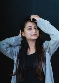 Portrait of beautiful young woman against black background