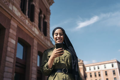 Young woman standing against building